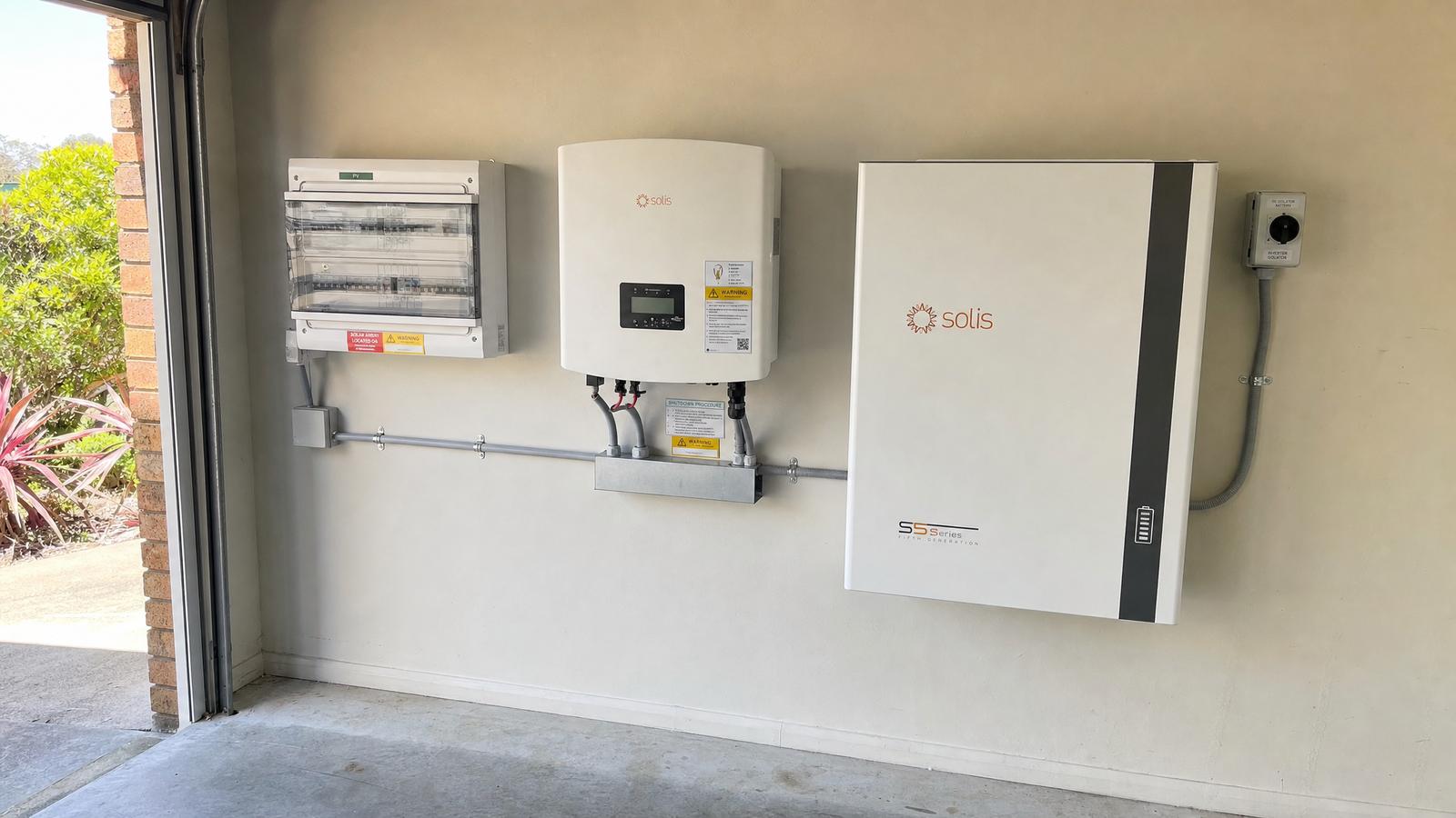 Completed home battery and inverter installation in an Australian garage, showing neat conduit runs and switchboard